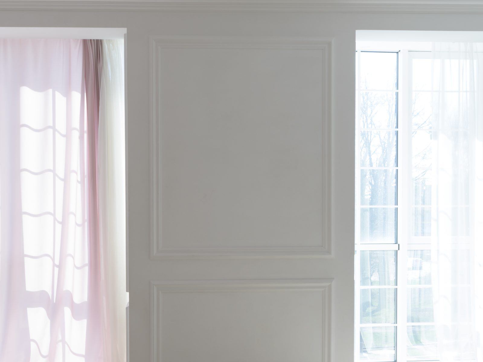 A white panelled wall between two windows